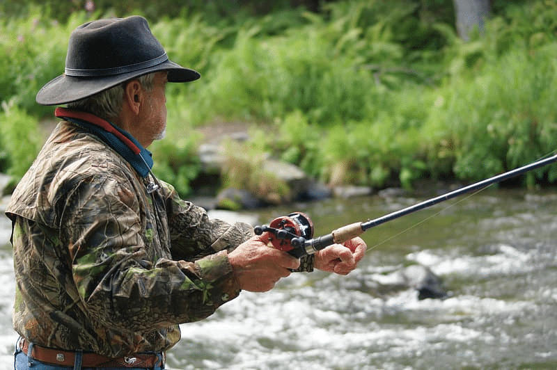 Fishing rod with a reel in the hands of a fisherman on Alaskan waters