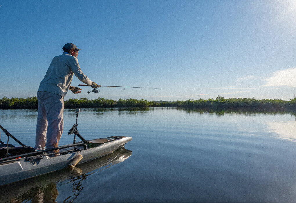 man fishing while standing from his kayak