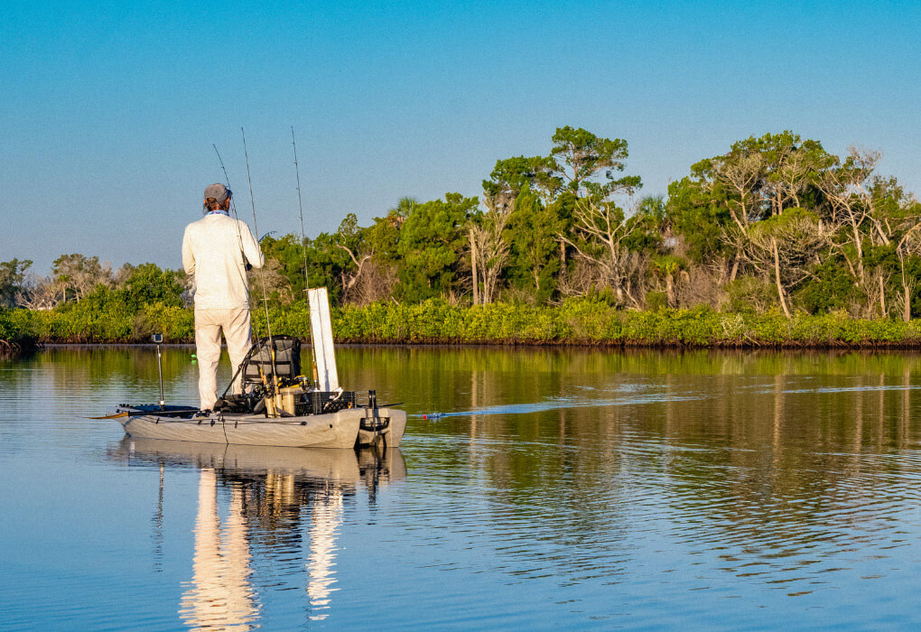 fisherman standing up while fishing in his kayak