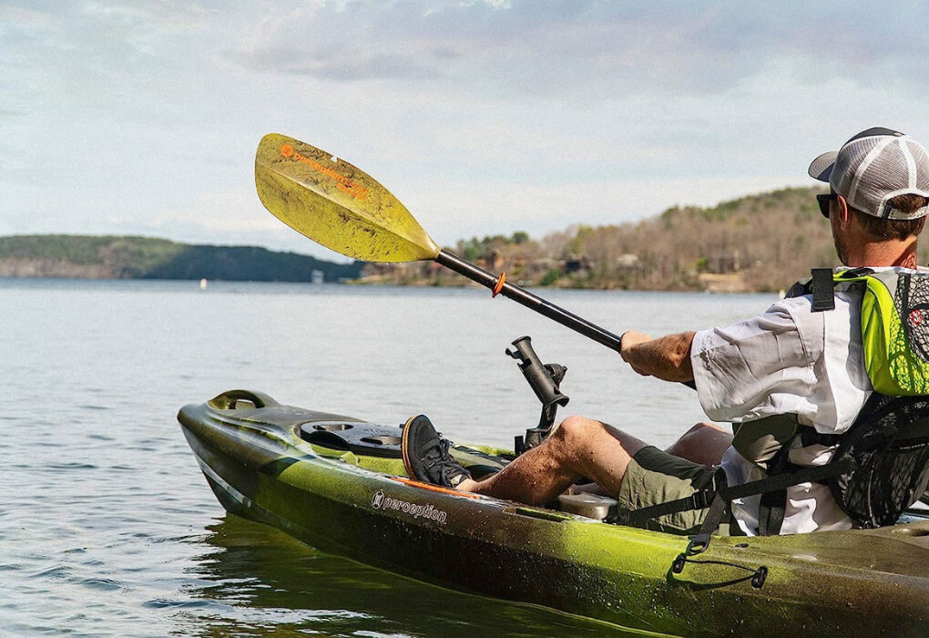 man padding while sitting in a fishing kayak