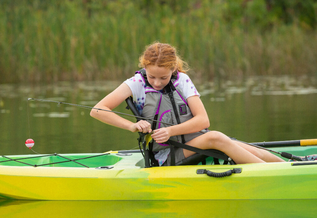 fisher young lady wearing a fishing pfd in her fishing kayak