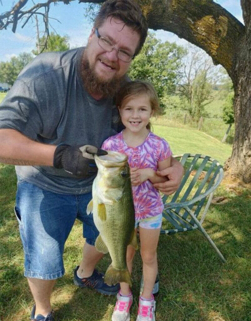 With a little help from dad, LayLa Pulis, 6, shows off the big bass she caught on a farm pond