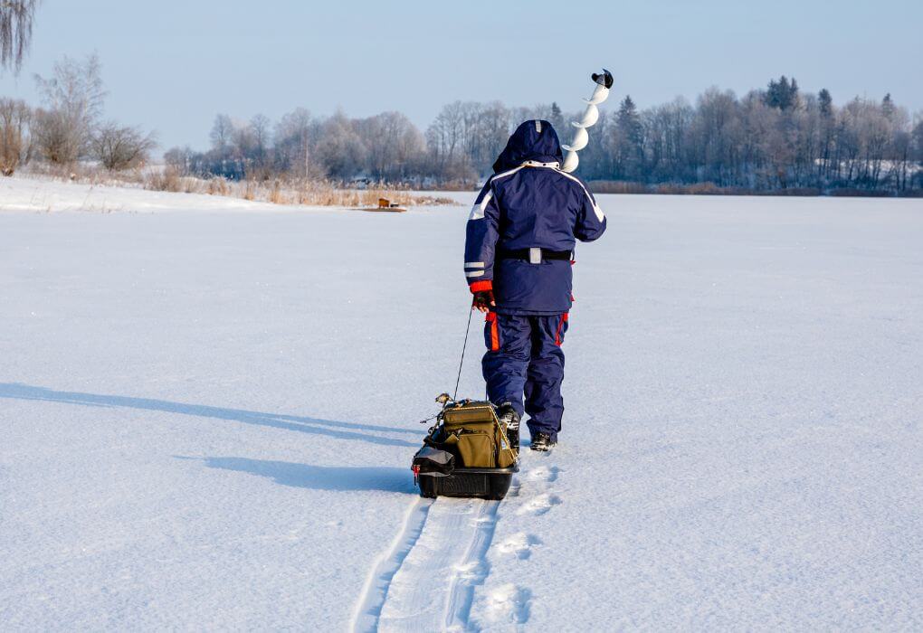 man pulling his ice fishing sled on snow